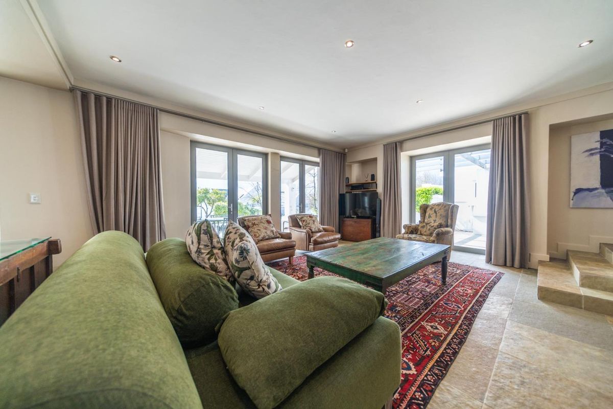 Spacious living room featuring stone flooring, recessed lighting, and multiple sets of double-glazed french doors providing ample natural light and access to the outdoors.