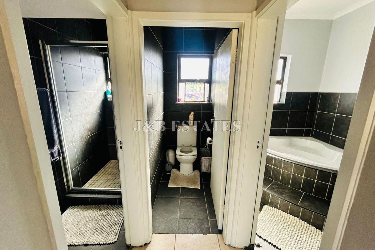 A modern bathroom layout featuring a separate shower cubicle, a private toilet area, and a corner bathtub with dark tiled finishes.