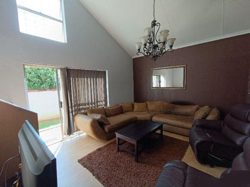 Spacious living room featuring a vaulted ceiling, laminate flooring, and a large sliding glass door providing access to the outdoor area.