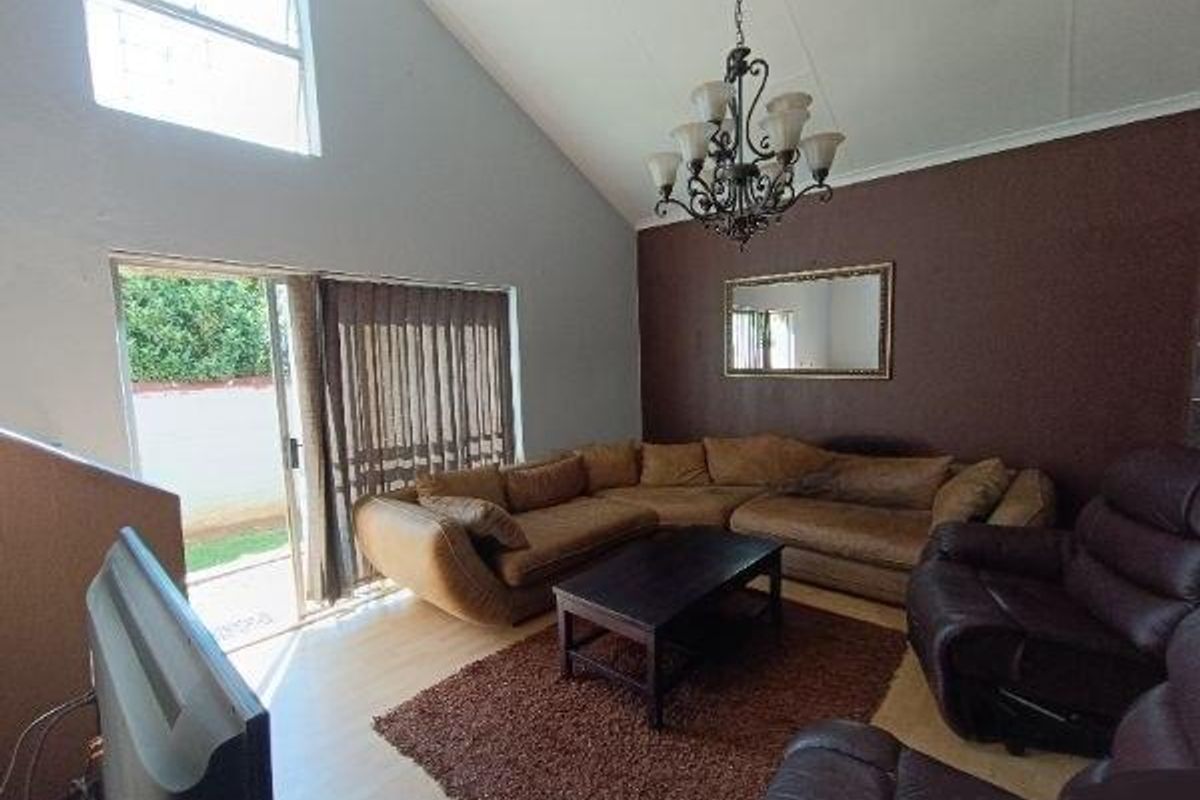 Spacious living room featuring a vaulted ceiling, laminate flooring, and a large sliding glass door providing access to the outdoor area.