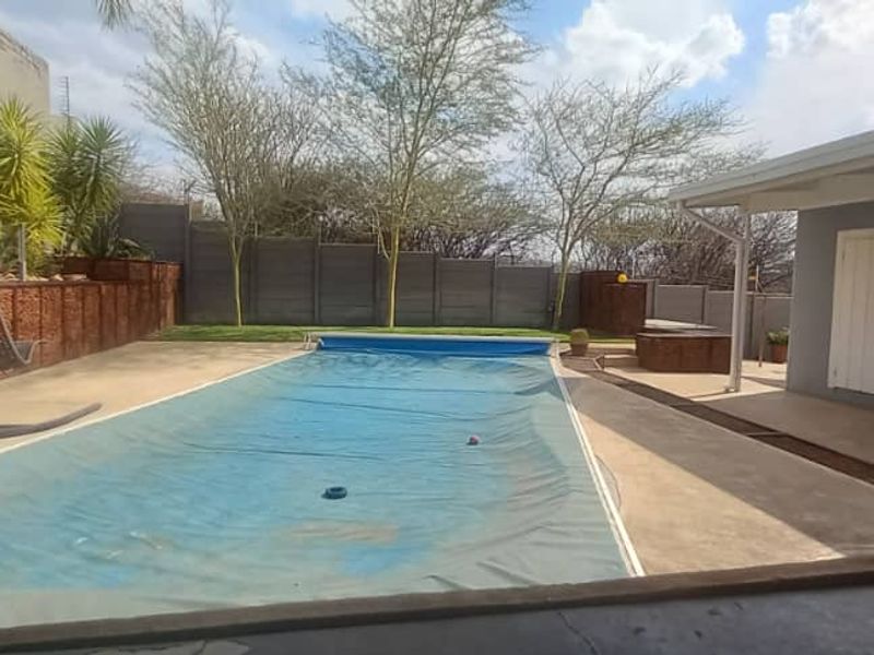 Outdoor pool area featuring a swimming pool with a cover, paved patio space, and perimeter fencing, providing a private backyard setting.
