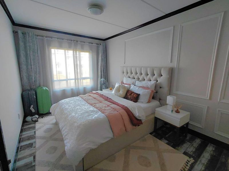 A well-maintained bedroom featuring decorative wall wainscoting and a central ceiling light fixture, providing a comfortable and finished living space.
