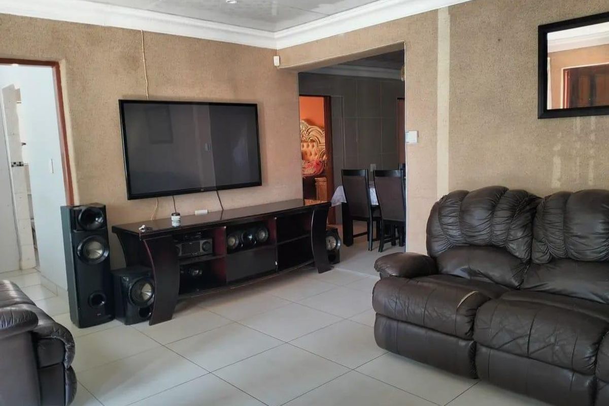 Spacious living area featuring large format floor tiles and textured wall finishes, providing an open layout with direct access to adjacent rooms.