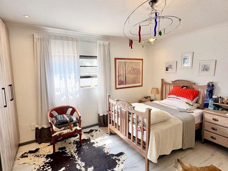 A well-maintained bedroom featuring light-toned laminate flooring, built-in cupboards, and recessed ceiling lighting, offering a clean and functional living space.