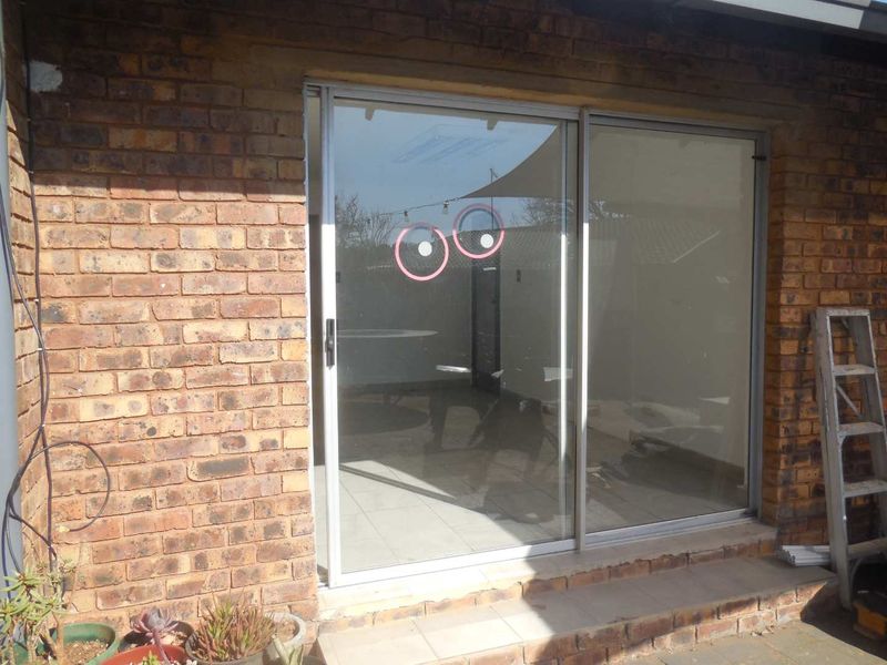 Rear exterior view of the office building featuring a sliding glass door set into a face brick facade with a tiled threshold.