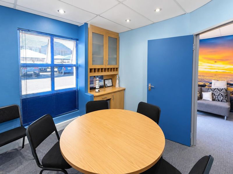 A functional office space featuring a suspended ceiling with recessed lighting, built-in cabinetry, and a window with venetian blinds.