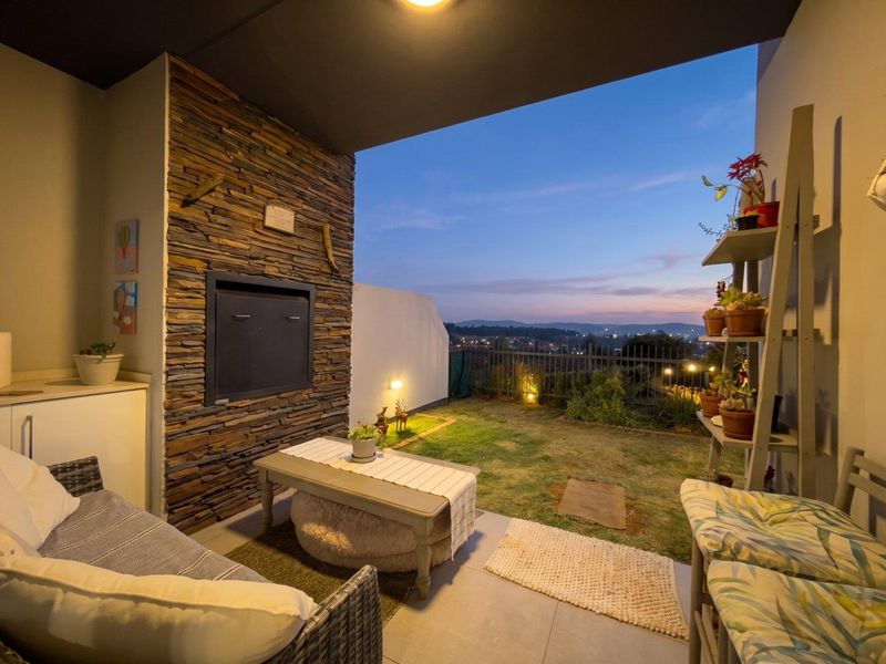 Covered patio featuring a built-in braai with stone cladding, tiled flooring, and direct access to a private garden area with scenic views.