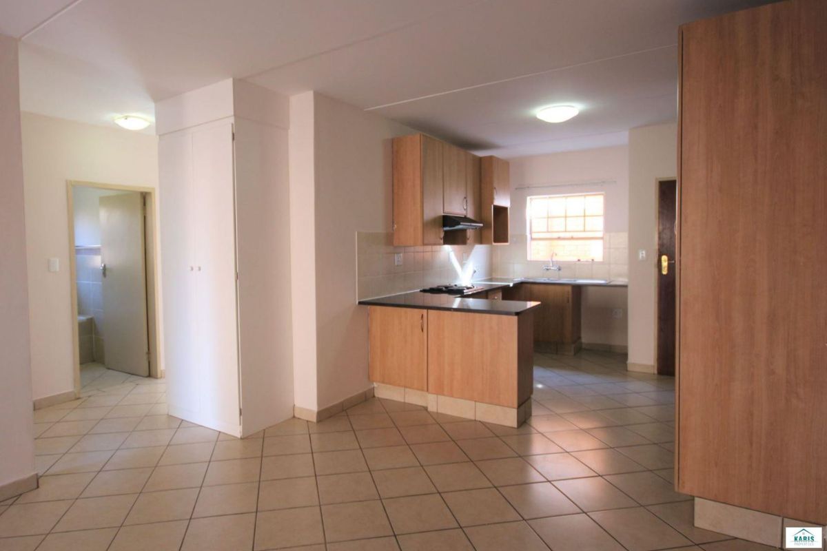 Open plan kitchen area featuring light wood cabinetry, laminate countertops, built-in hob, extractor fan, and tiled flooring throughout.