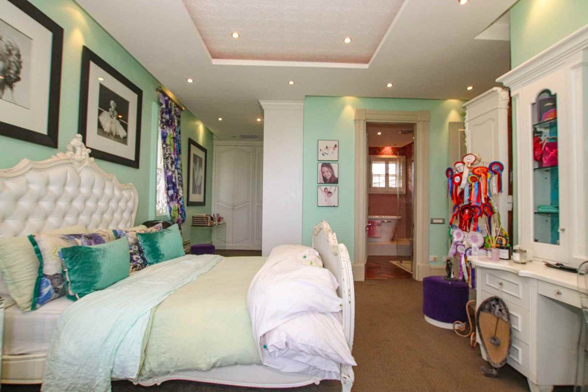 Spacious bedroom featuring a recessed ceiling with integrated downlights, built-in cabinetry, and an en-suite bathroom with a visible bathtub.