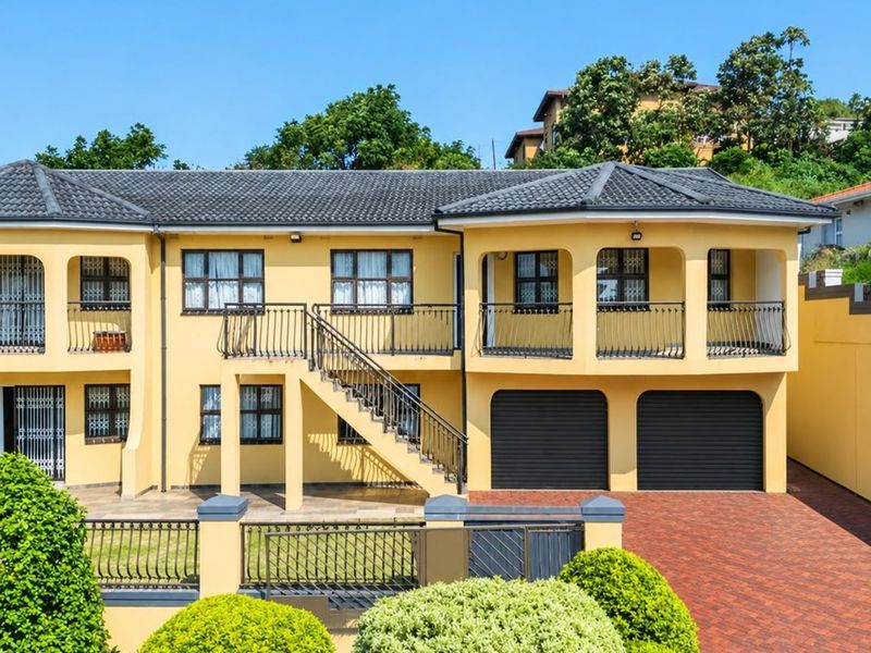 A well-maintained double-story residential property featuring a paved driveway, double garage, and covered balconies with wrought iron railings.