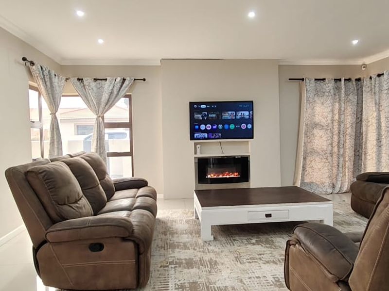 A well-maintained living room featuring tiled flooring, recessed downlighting, and a central feature wall with a built-in electric fireplace.