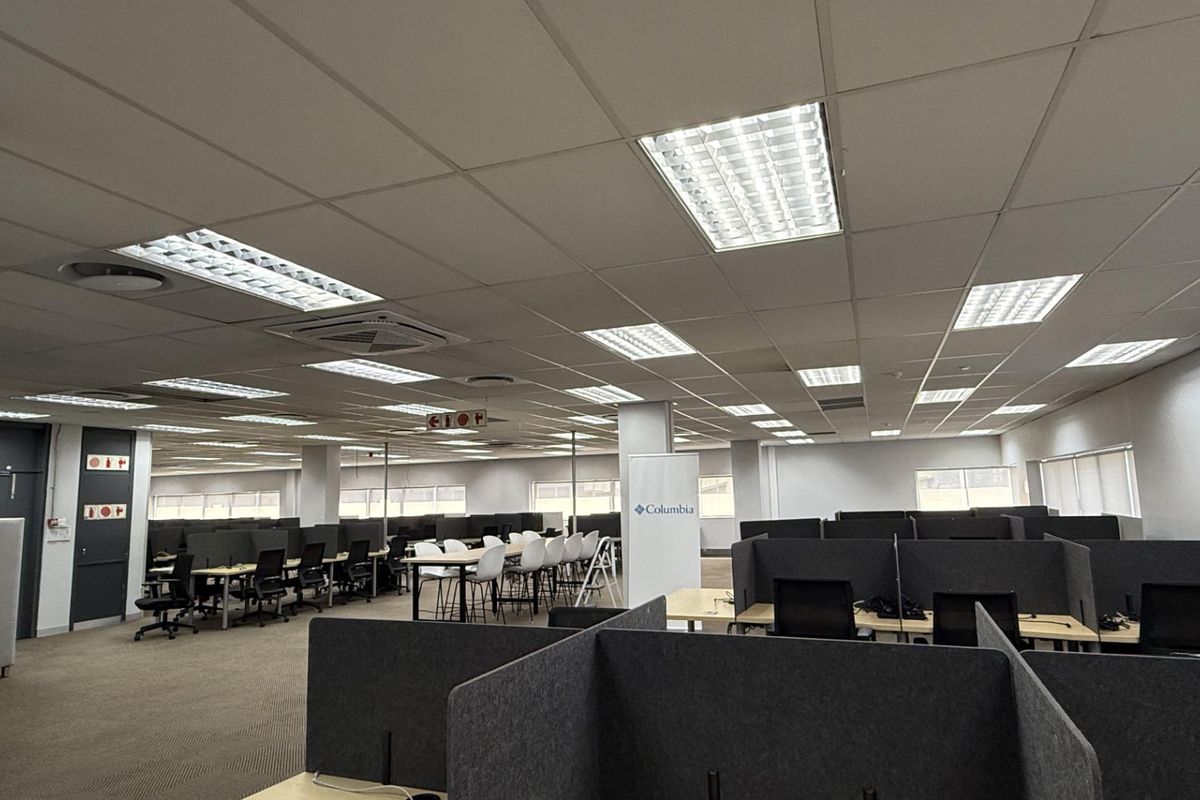 Spacious open-plan office area featuring suspended ceilings, recessed lighting, central air conditioning, and integrated workstation partitions.