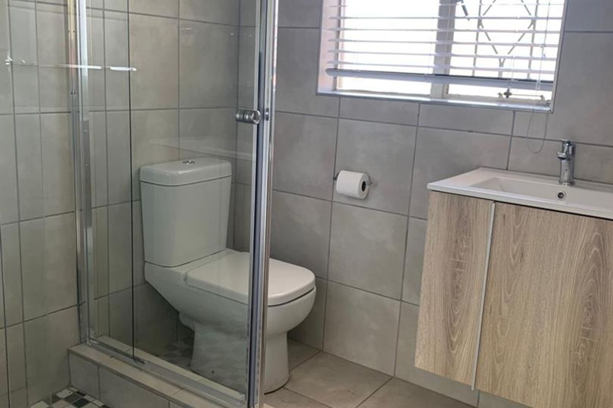 Modern bathroom featuring a glass-enclosed shower with mosaic floor tiles, a wall-mounted vanity, and a toilet.