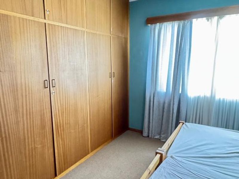 Bedroom featuring extensive built-in wooden cabinetry, a ceiling fan, and carpeted flooring, offering functional storage space.