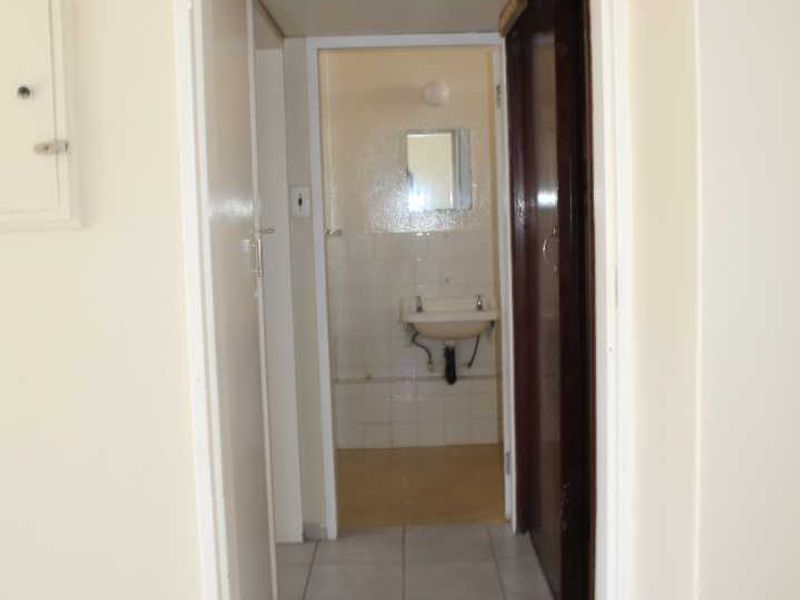 A functional hallway leading to a bathroom, featuring tiled flooring and built-in storage cupboards.