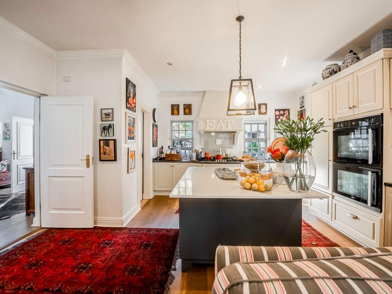 A well-appointed kitchen featuring a central island, stone countertops, shaker-style cabinetry, and a built-in double oven, finished with elegant pendant lighting.