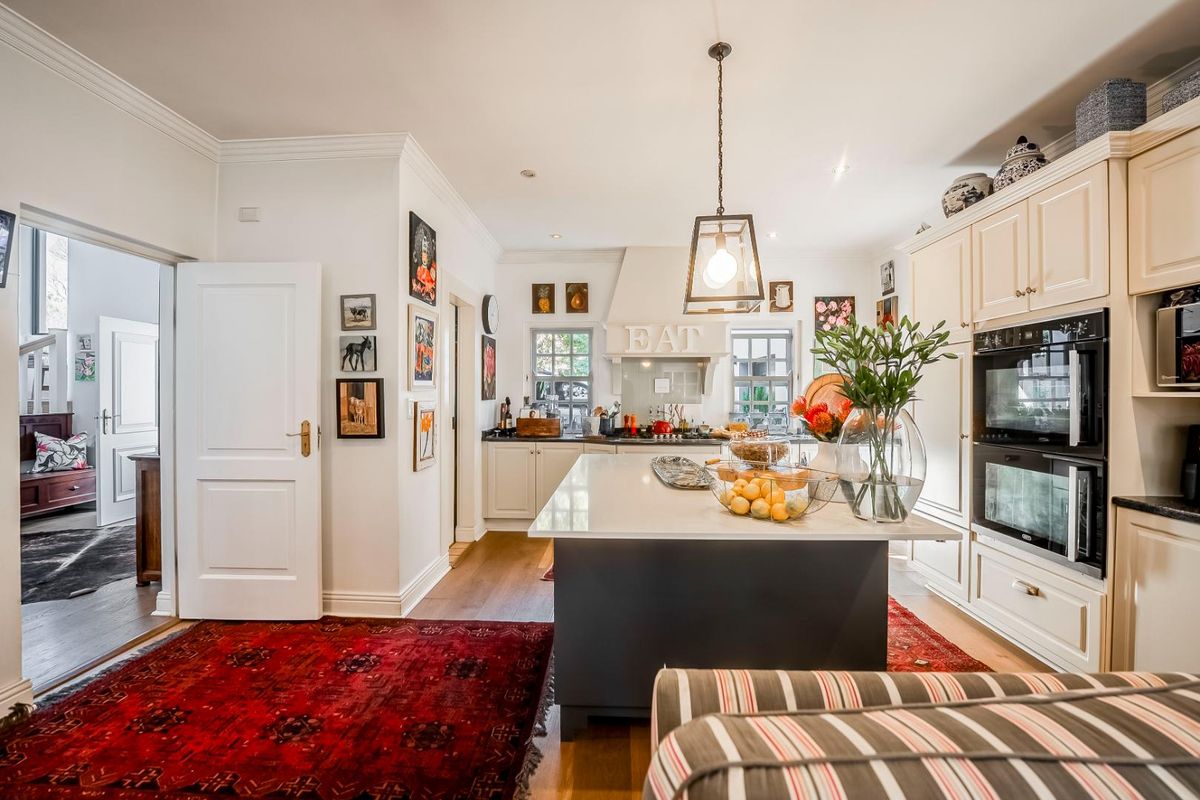 A well-appointed kitchen featuring a central island, stone countertops, shaker-style cabinetry, and a built-in double oven, finished with elegant pendant lighting.
