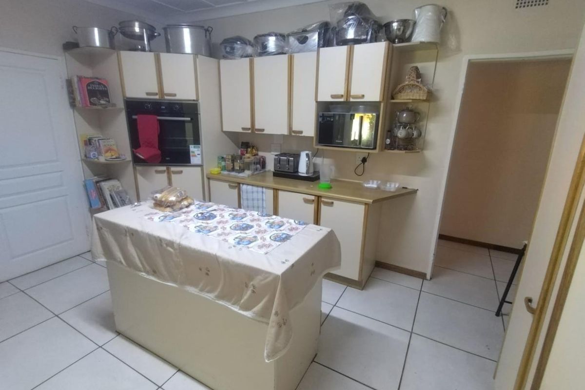 A functional kitchen featuring built-in oven and microwave, laminate countertops, and tiled flooring, offering a dated aesthetic ready for modern updates.