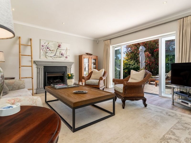 A bright and inviting living room featuring a stone fireplace, hardwood flooring, and large sliding glass doors that open to an outdoor patio area.