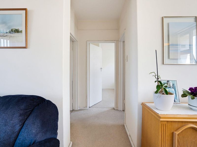 A neutral hallway connecting multiple rooms, featuring carpeted flooring and standard internal doors.