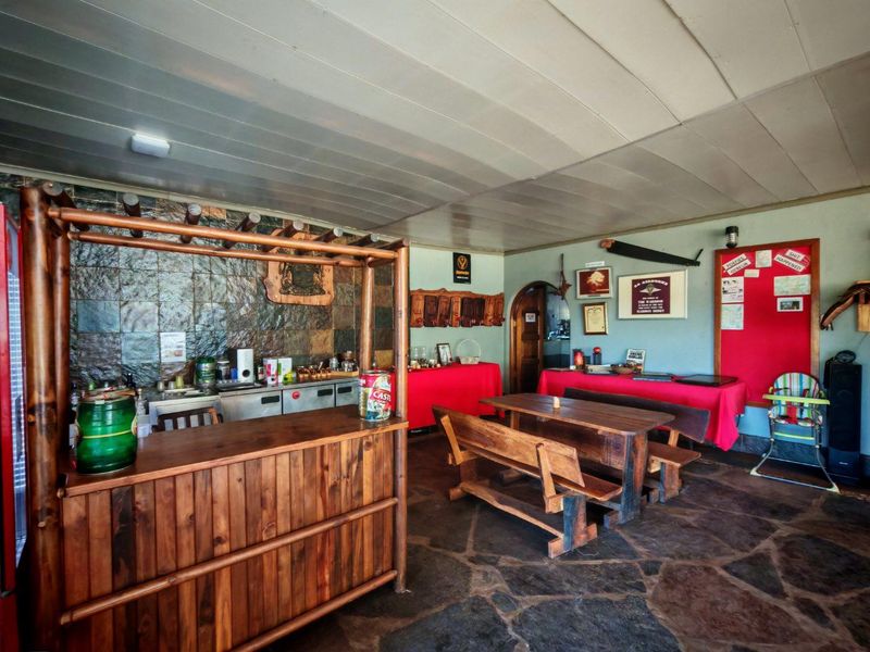A rustic bar area featuring flagstone flooring, stone-clad wall accents, and a built-in wooden bar counter, creating a traditional pub-style atmosphere.