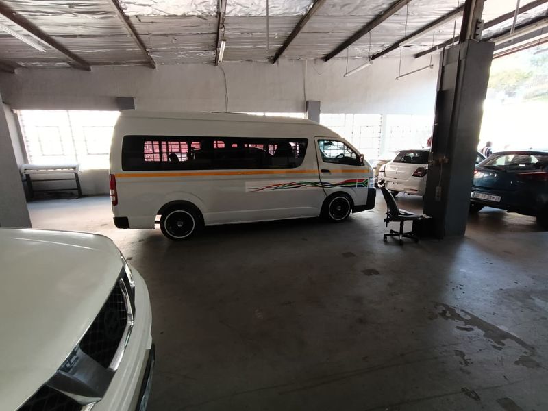 Spacious industrial garage area featuring exposed steel roof trusses, concrete flooring, and structural support columns, suitable for vehicle storage or workshop use.