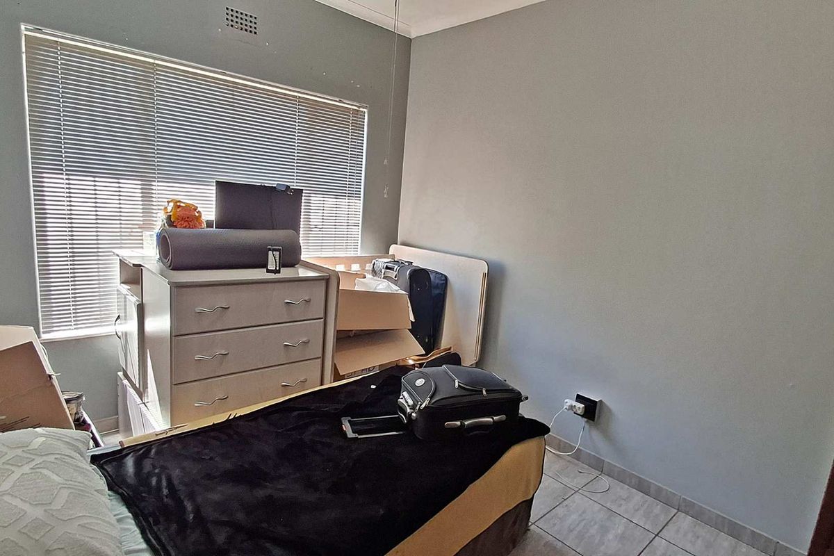 A bedroom featuring tiled flooring, venetian blinds, and neutral wall finishes, providing a functional space ready for personalization.