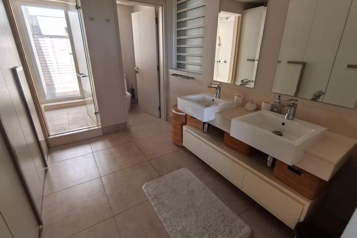 Modern bathroom featuring a double vanity with vessel sinks, tiled flooring, and a separate glass-enclosed shower area.