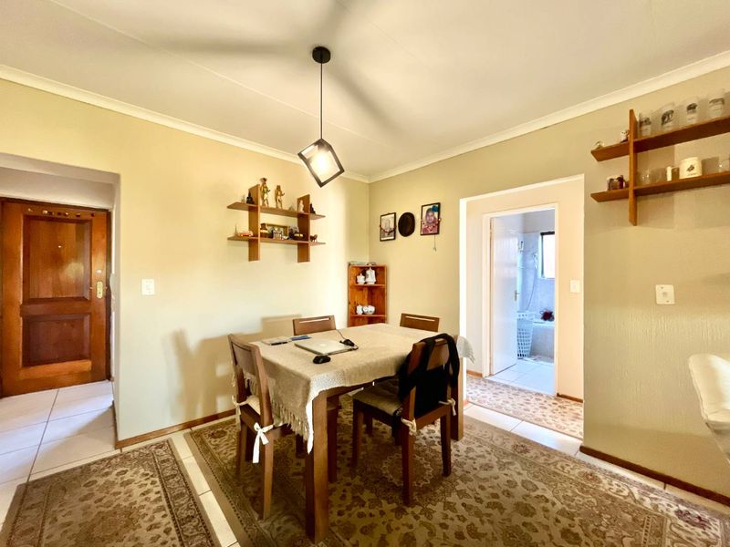 Dining area featuring tiled flooring, a central pendant light, and built-in wall shelving, with an adjacent view into a bathroom.