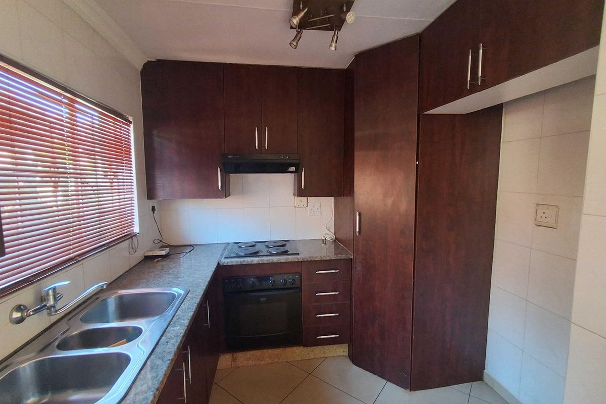 A functional kitchen featuring dark wood-look cabinetry, granite countertops, a double stainless steel sink, and built-in oven with electric hob.