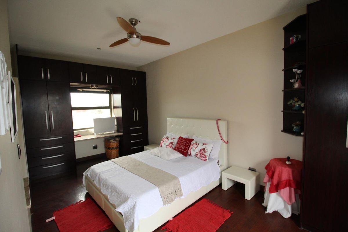 A bedroom featuring dark wood built-in cabinetry, a ceiling fan, and dark wood flooring.