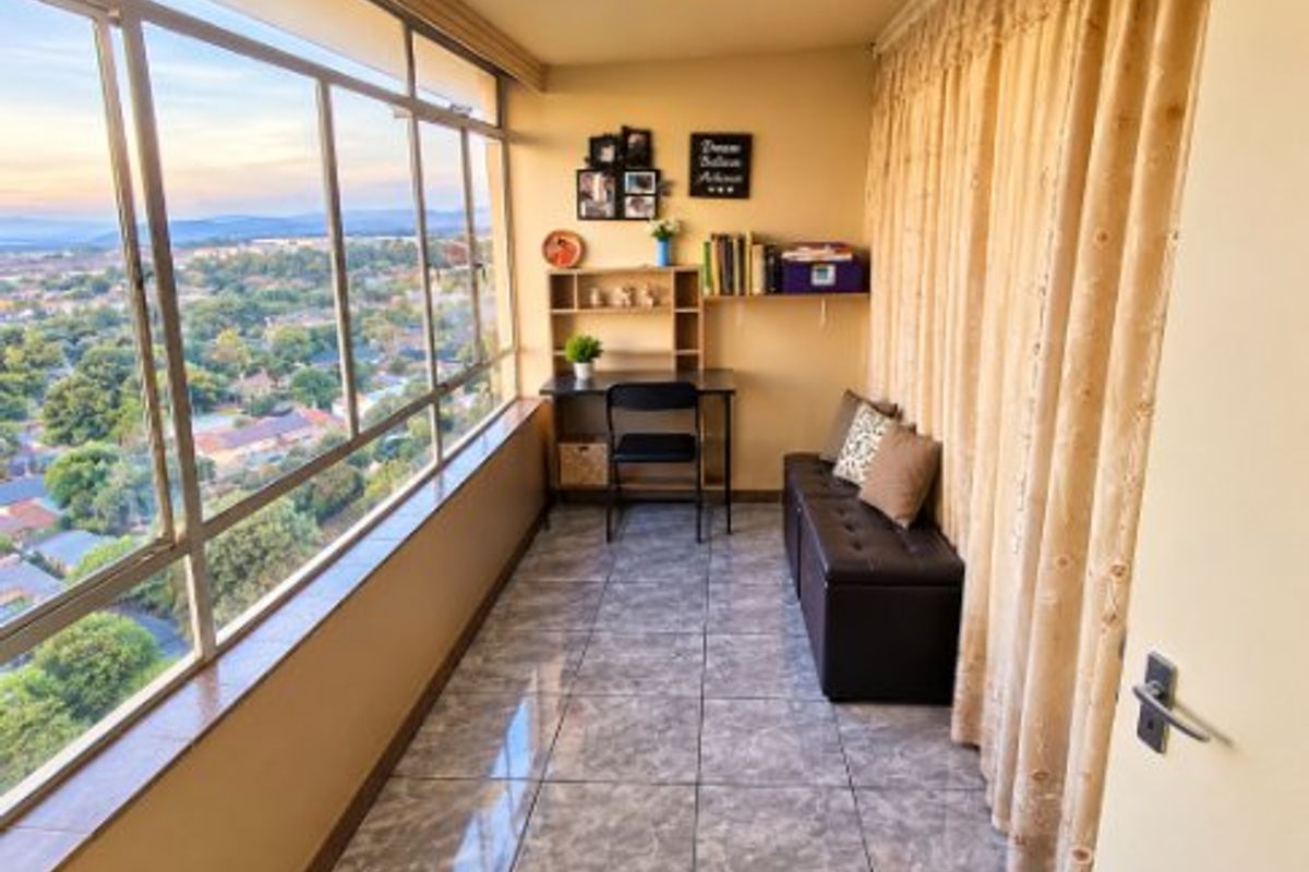 Enclosed balcony featuring large glass windows with panoramic views and tiled flooring, suitable for use as a sunroom or home office space.