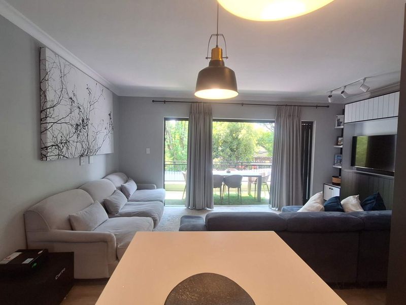 Open plan living area featuring neutral walls, modern lighting, and a large sliding door providing access to an outdoor patio space.
