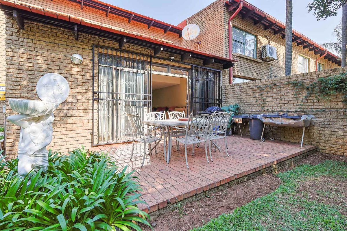 A private rear patio area featuring brick paving, security gates, and direct access to the interior living space.