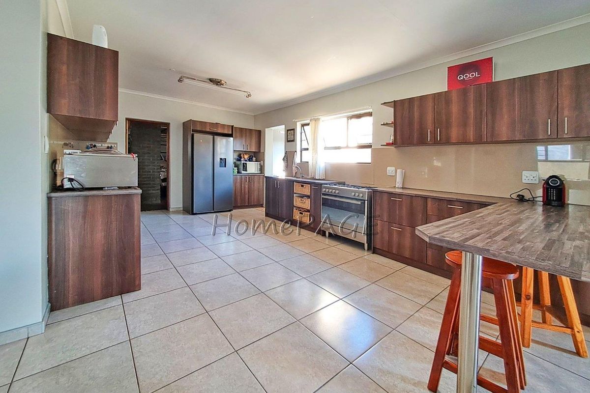 Spacious kitchen featuring dark wood cabinetry, tiled flooring, a built-in stove, and a breakfast bar counter.