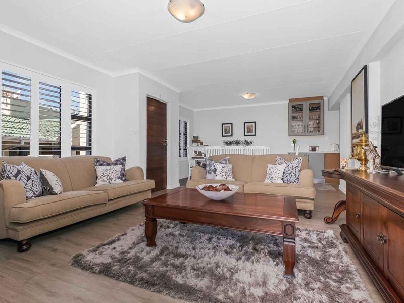 Spacious open-plan living and dining area featuring modern laminate flooring, plantation shutters, and built-in cabinetry, offering a bright and well-maintained living space.