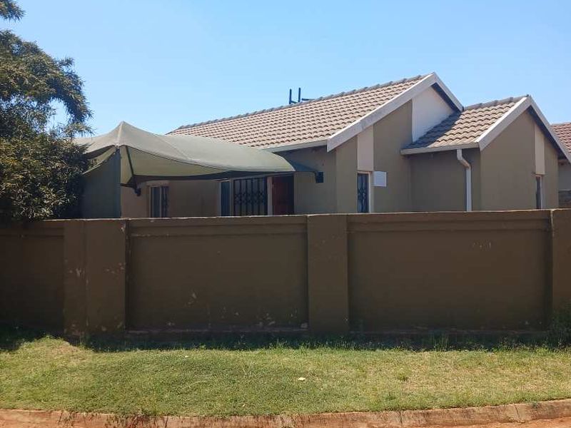 Front view of a residential house featuring a tiled roof, perimeter wall, and an installed shade sail over the entrance area.