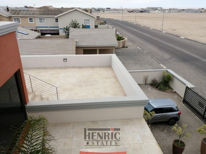 An elevated, tiled balcony area featuring a modern stainless steel balustrade and parapet wall, offering an open outdoor space.