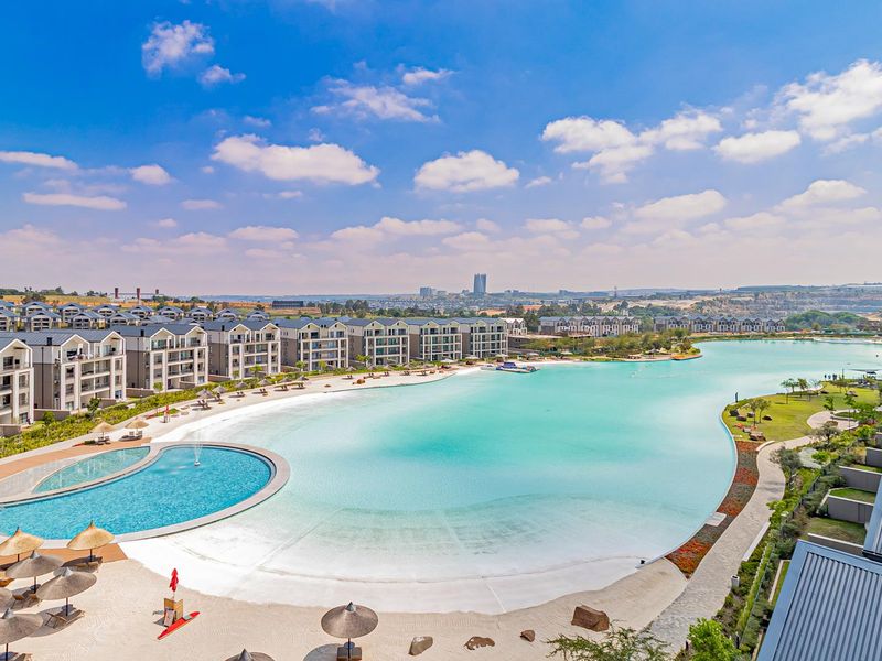 Aerial view of a luxury residential estate featuring a large man-made lagoon, swimming pool, and extensive landscaped grounds.