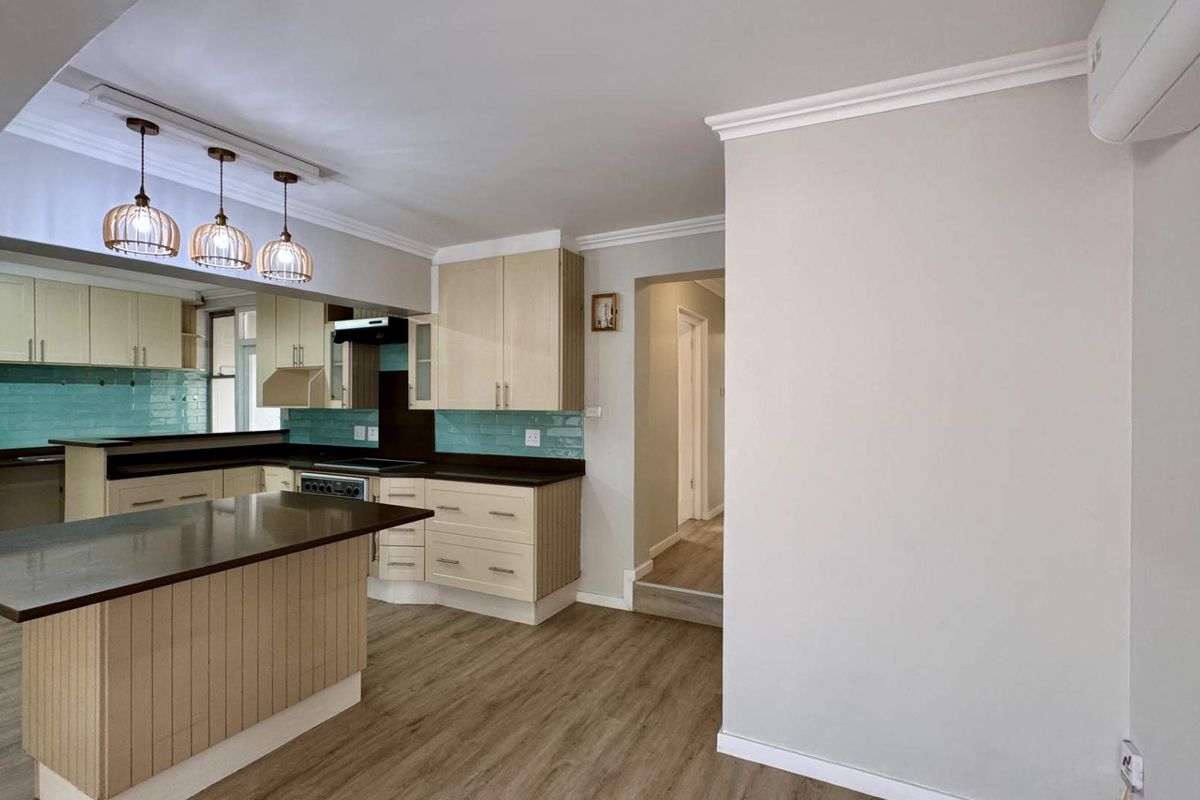 Modern kitchen featuring light wood cabinetry, dark laminate countertops, a breakfast island, and a vibrant teal subway tile backsplash.