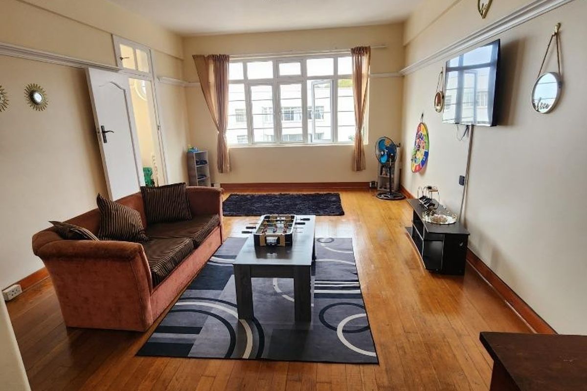 Spacious living room featuring original hardwood flooring, picture rails, and large windows providing natural light.