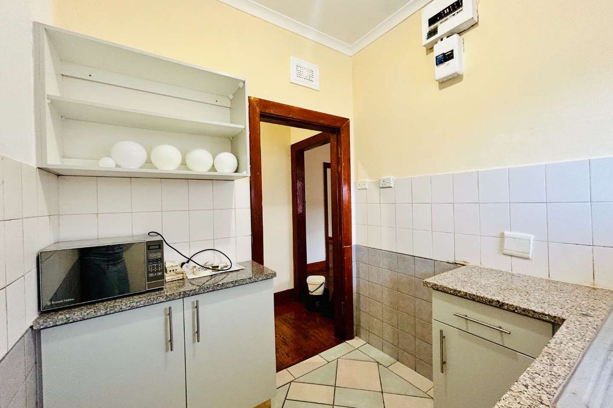 A functional kitchen featuring granite countertops, tiled splashbacks, and built-in cabinetry, providing a practical workspace with an adjacent hallway access.
