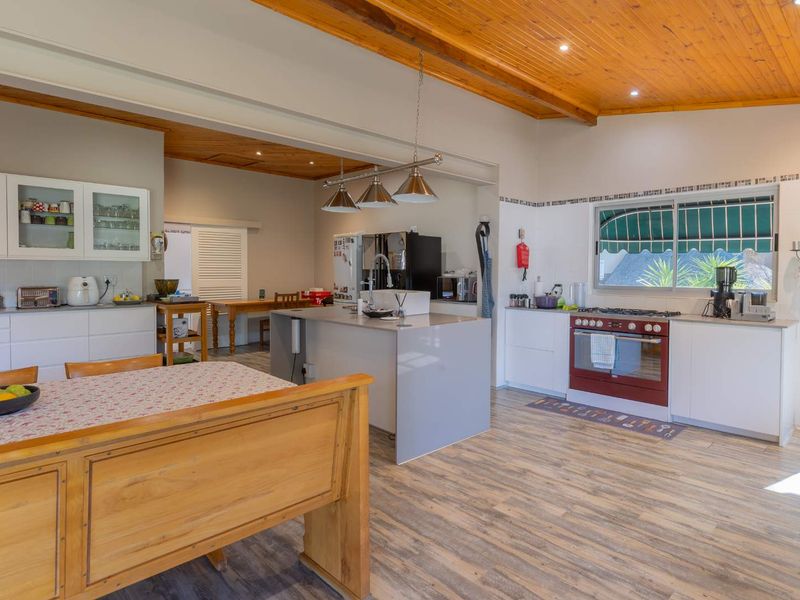 Spacious open-plan kitchen and dining area featuring a central island, modern cabinetry, gas oven, and warm timber ceiling finishes.
