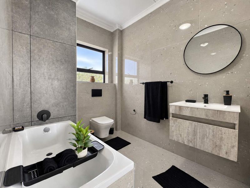 Modern bathroom featuring high-end terrazzo-style tiling, a floating vanity, wall-mounted toilet, and a built-in bathtub with contemporary black matte fixtures.