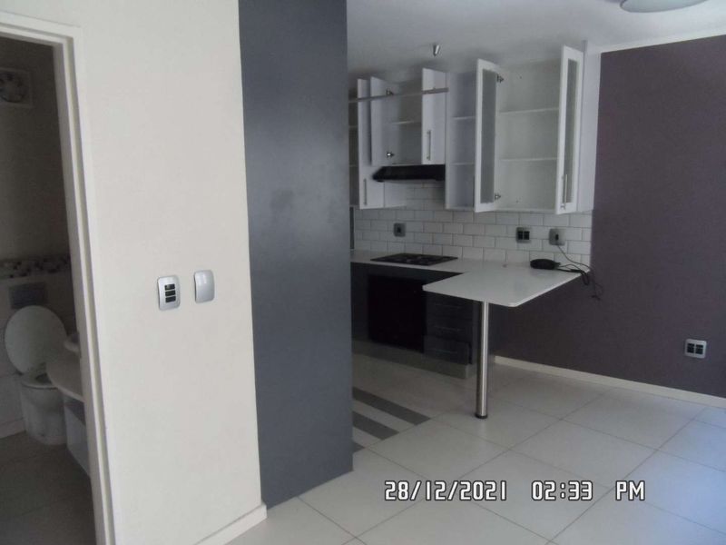 Open plan kitchen area featuring built-in cabinetry, a breakfast bar, and subway tile backsplash, adjacent to a small bathroom with a toilet.