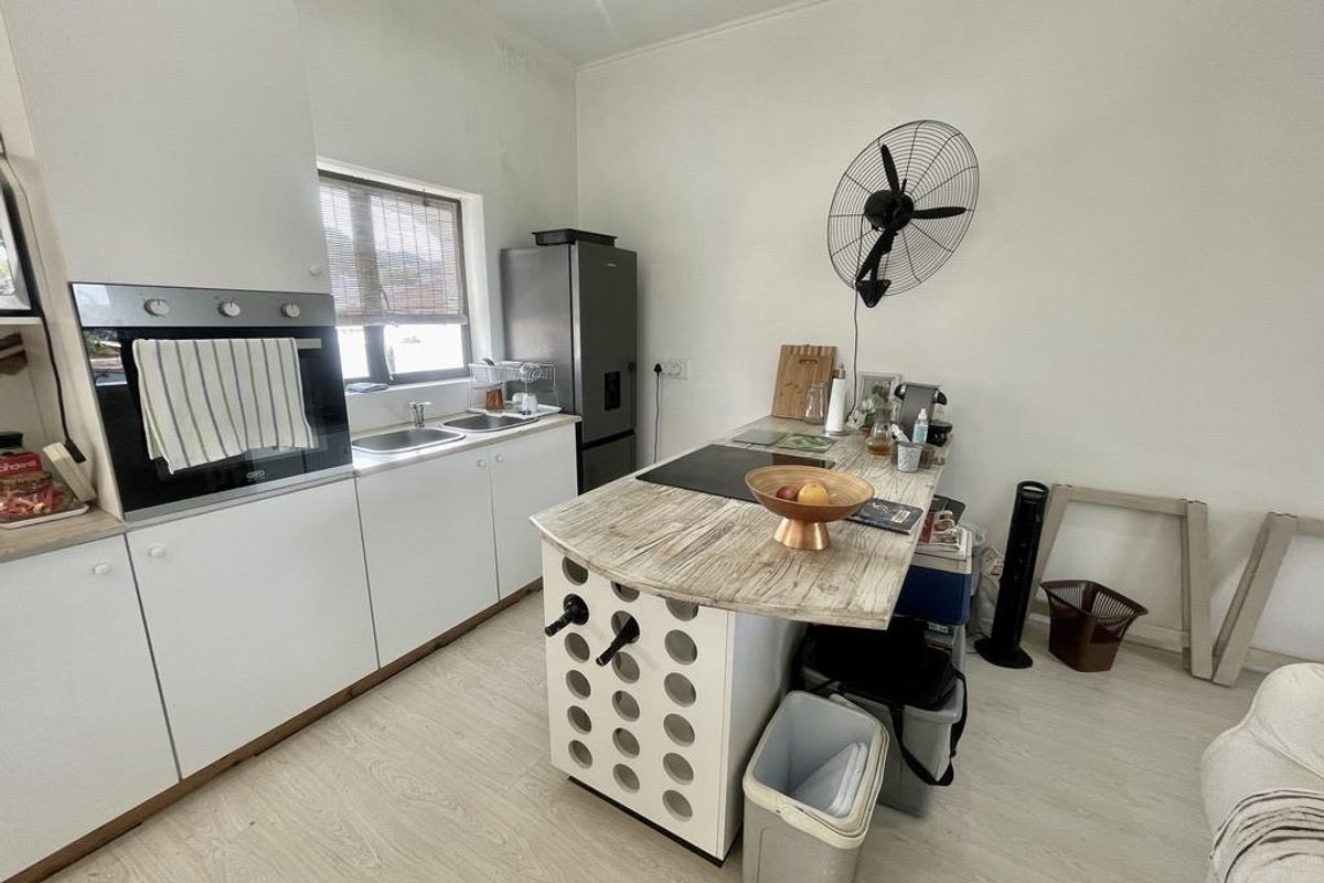 A functional kitchen featuring white cabinetry, a built-in oven, a double sink, and a central island with a wood-look countertop.