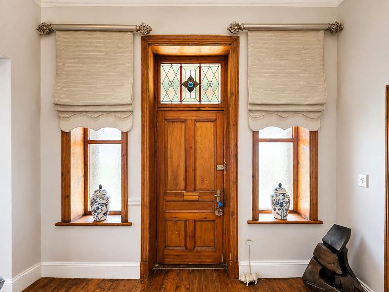 A classic entryway featuring a solid timber front door with a decorative stained glass transom window and matching timber-framed side windows.
