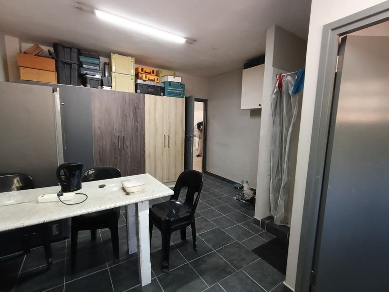 A functional utility space featuring tiled flooring, built-in cabinetry for storage, and an integrated shower area, suitable for various industrial or workshop support uses.