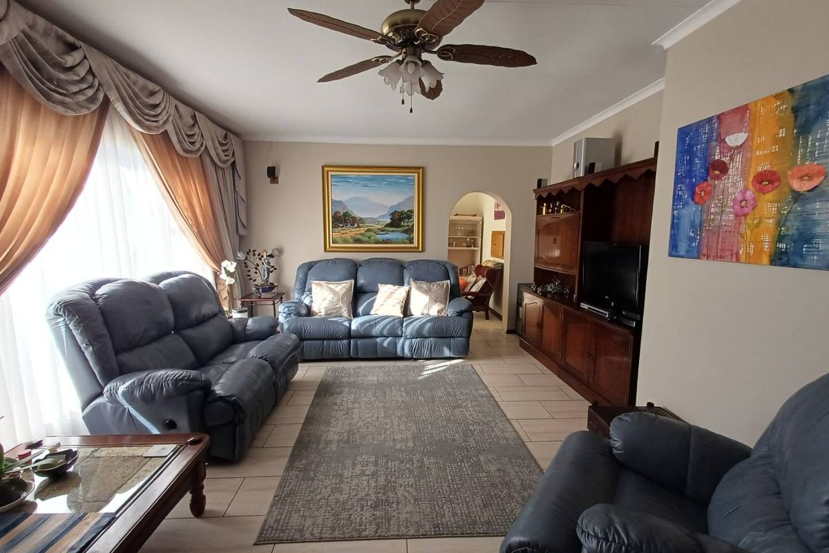 A spacious living room featuring tiled flooring, a ceiling fan, and an arched doorway leading to an adjacent area.