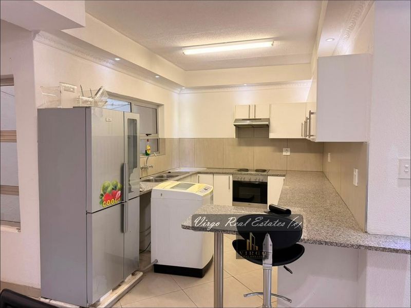 Functional kitchen featuring granite countertops, built-in cabinetry, integrated oven and hob, and a convenient breakfast bar for casual dining.